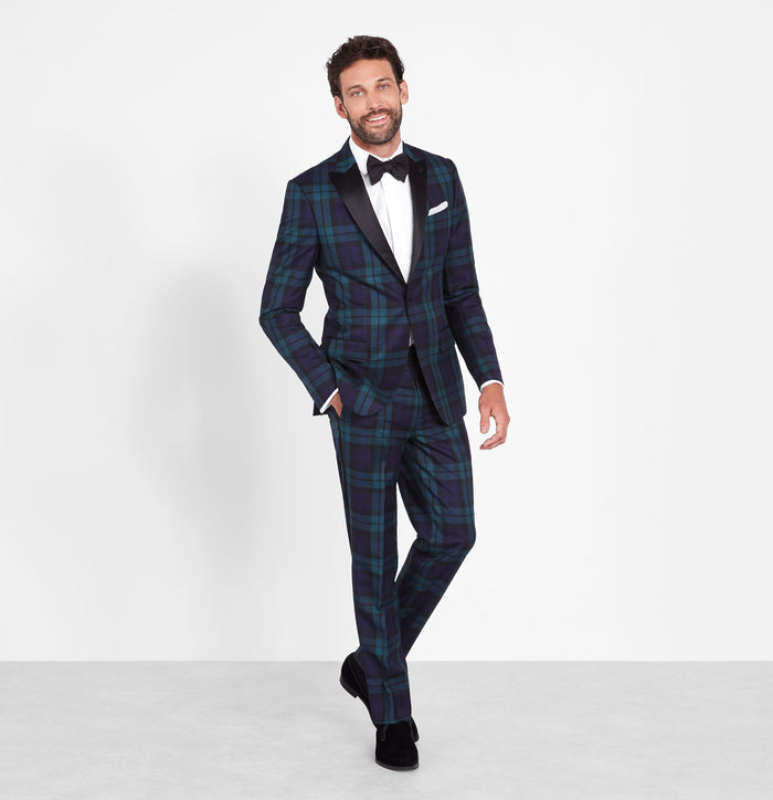 Man in a black watch tartan tuxedo, full-length front view, white background.
