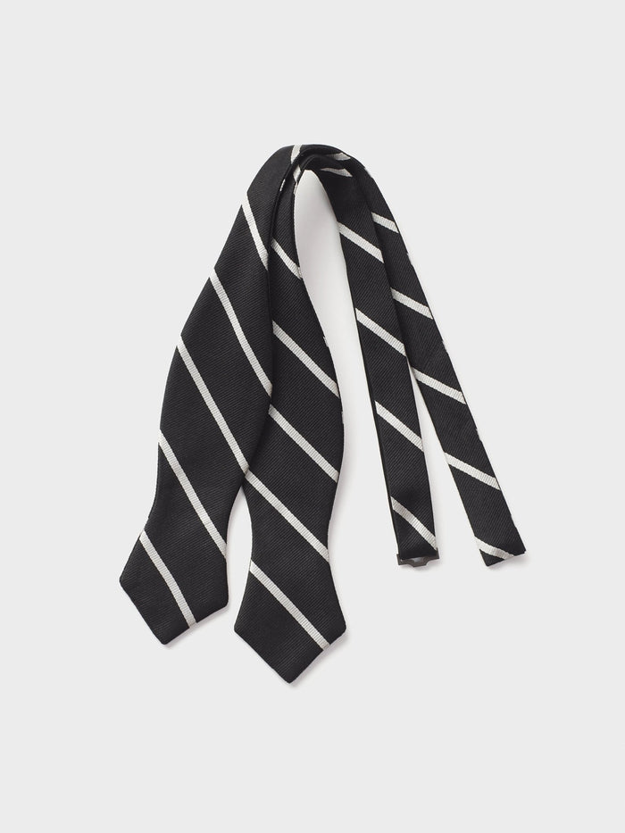 Untied black silk bow tie with white diagonal stripes, laid flat on a grey background.