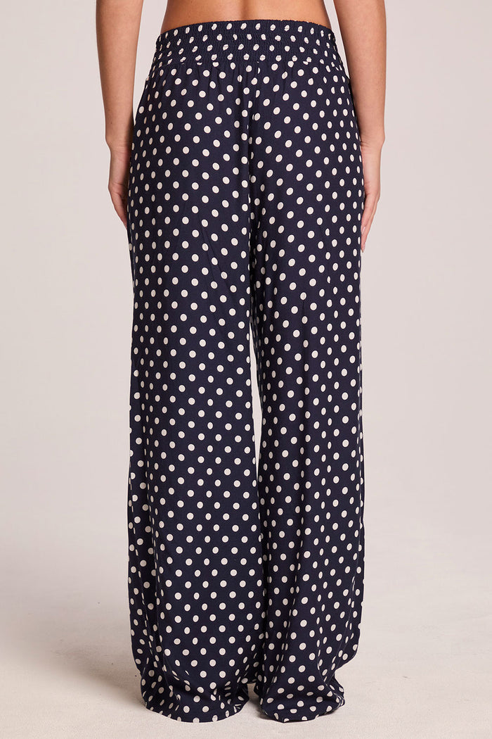 Back view of a woman wearing the Chaser  Blair Navy Spot Trouser on a neutral background with hands at her sides
