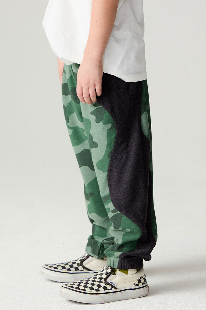 Side view of a boy wearing the Chaser Blocked Camo Pants Boys Jogger on a neutral background with white tee