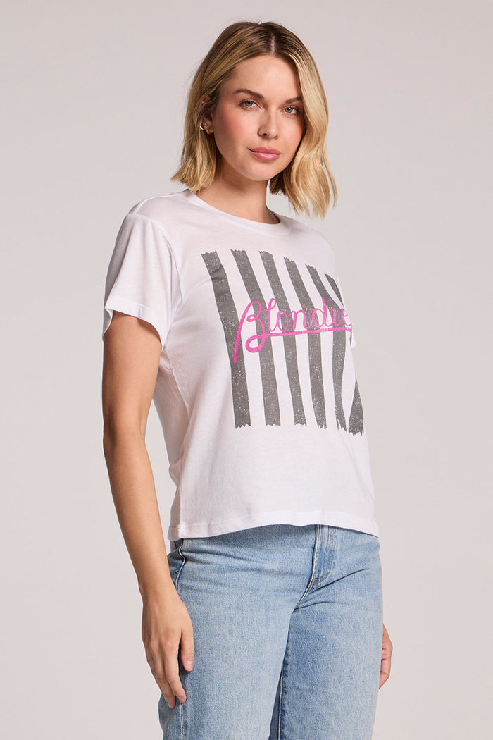 Side angle view of a woman wearing the Chaser  Blondie Parallel Lines Tee on a neutral background with arms at her side