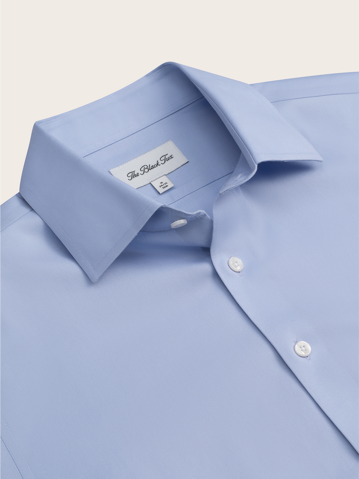 Close-up of a light blue dress shirt's spread collar and brand tag.