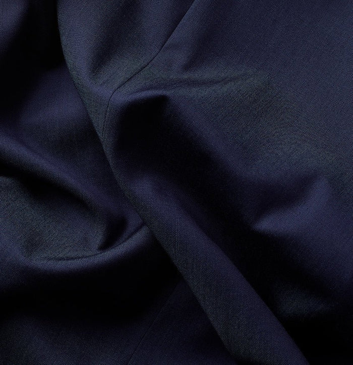 Close-up of blue suit jacket fabric with a visible seam and weave.