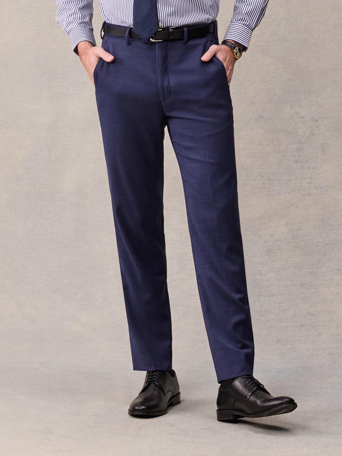 Cropped front view of a man in blue suit trousers, striped shirt, and black belt, hands in pockets