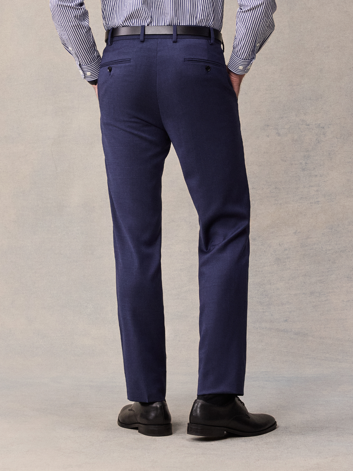 Cropped back view of a man in blue suit trousers with black belt and striped shirt