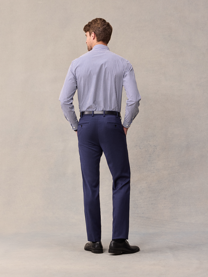 Back view of a man in a blue and white striped shirt and blue suit trousers.