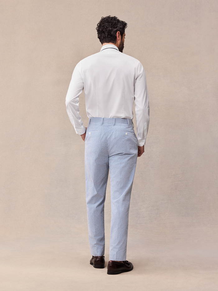 Back view of a man in blue and white striped seersucker trousers and white shirt.