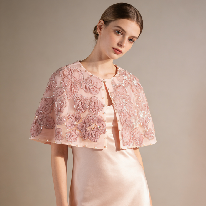 Handmade blush bridal cape with dimensional floral embroidery and delicate beadwork.