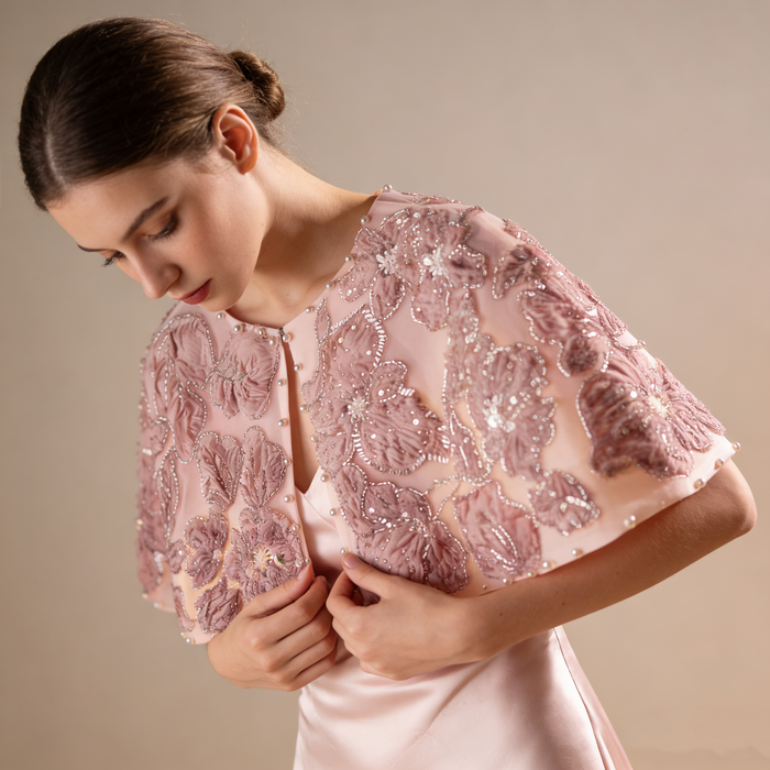 Luxury blush bridal cape featuring embroidered flowers, sequins and pearl accents.
