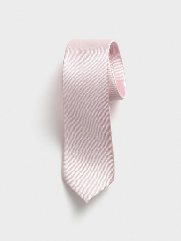 Blush silk necktie with twill texture, rolled at the top, on a grey background.