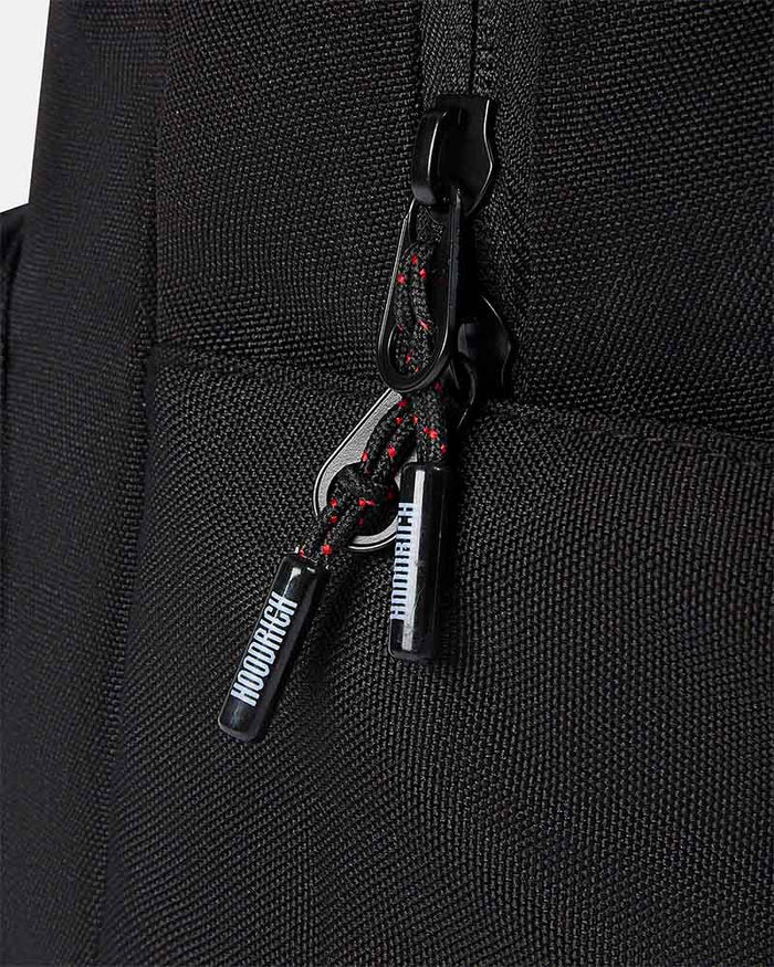 Close-up of a black woven fabric bag with a black zipper pull and a braided black-and-red zipper cord