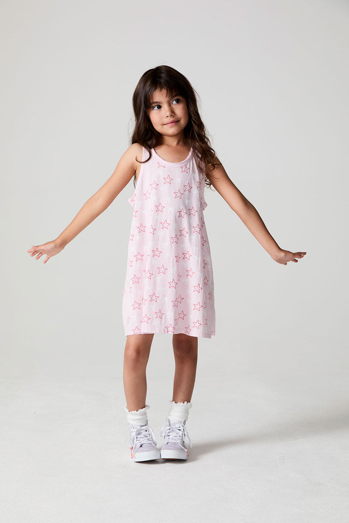 Front view of a girl wearing the Chaser Bows and Stars Dress and white sneakers and socks on a neutral background