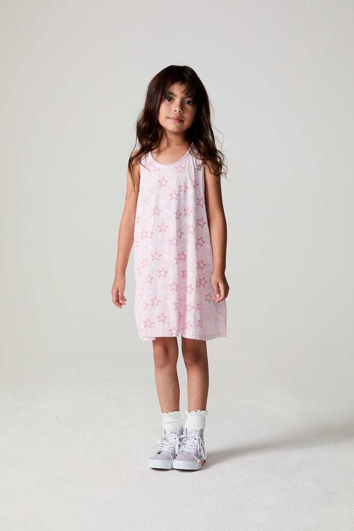 Front view of a girl wearing the Chaser Bows and Stars Dress and white sneakers on a neutral background