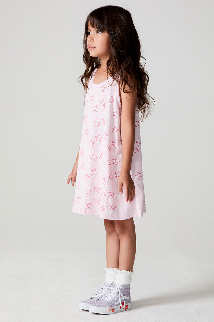 Side view of a girl wearing the Chaser Bows and Stars Dress on a neutral background with feet together and arms at her sides