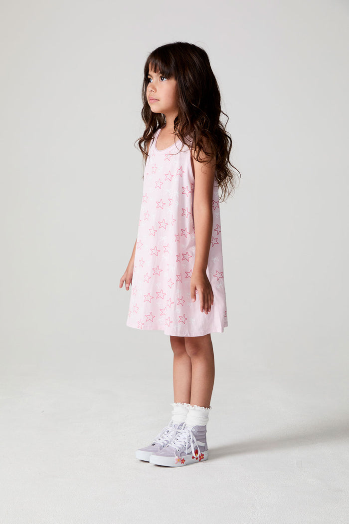 Side view of a girl wearing the Chaser Bows and Stars Dress on a neutral background with feet together