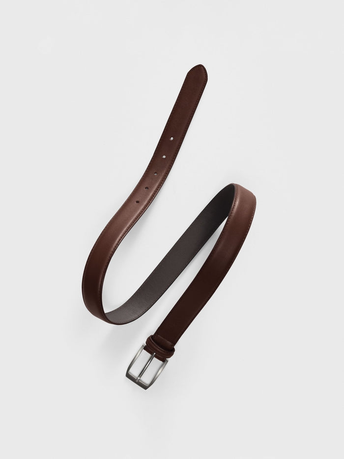 Brown leather belt coiled flat, silver rectangular buckle and punch holes visible.