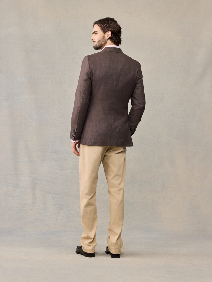 Back view of a man in a brown plaid sportcoat and tan trousers.
