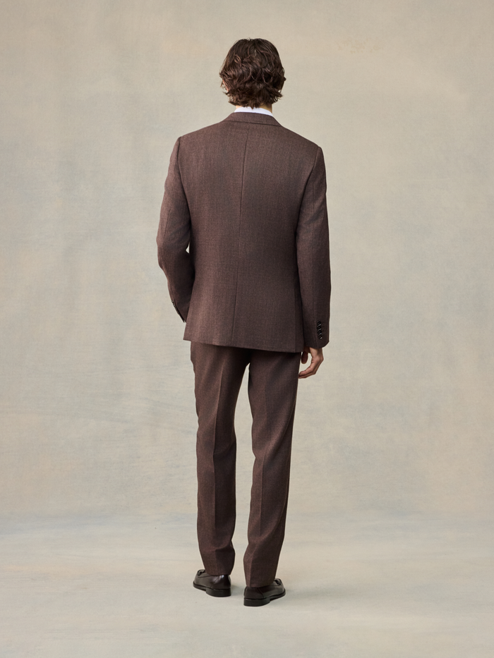 Back view of a man in a full brown puppytooth suit, full body.