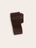 Brown silk knit tie rolled into a coil on a light background.