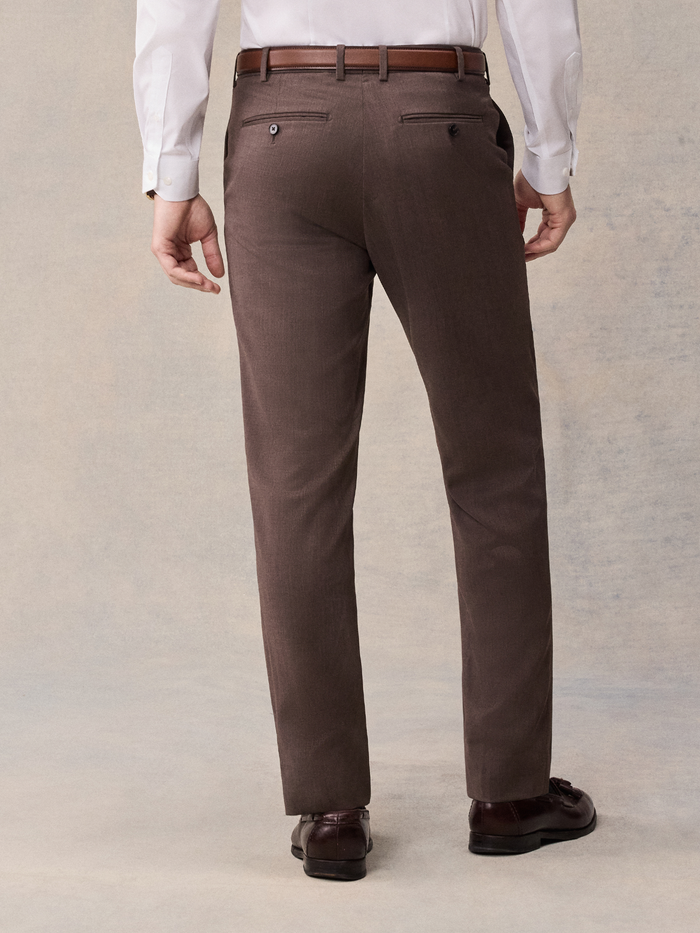 Cropped back view of a man in brown suit trousers with a brown belt.