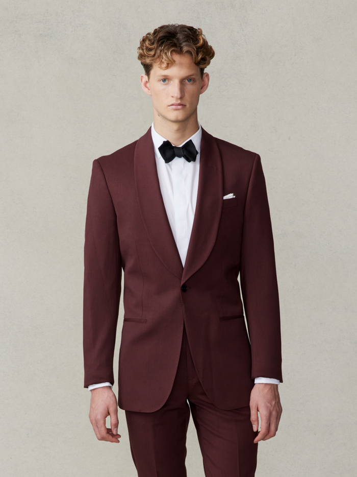 Man wearing a burgundy tuxedo with a black bow tie and white shirt.