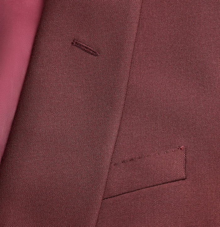 Close-up of a burgundy tuxedo jacket's lapel and pocket, pink lining visible.