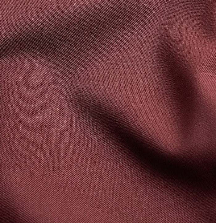 Close-up of burgundy tuxedo jacket fabric with folds and sheen.
