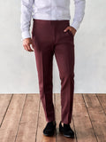 Cropped front view of a man in burgundy tuxedo trousers and a white shirt.