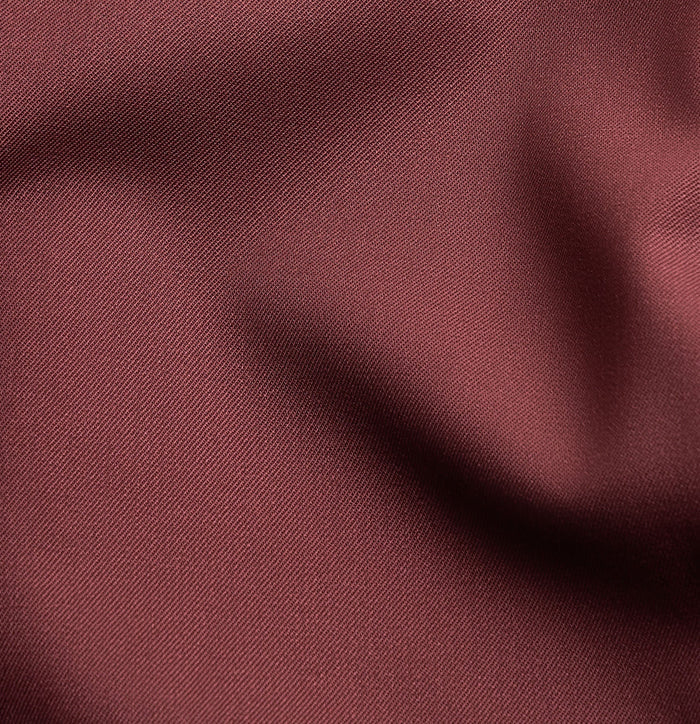 Close-up of burgundy tuxedo fabric with folds and satin sheen.
