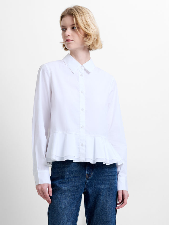 Woman wearing a white long sleeve shirt with a ruffled hem