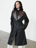 A woman wearing a double layer parka coat with contrast glossy lapels, long sleeves, a metal zip through fastening and 2 side pockets.