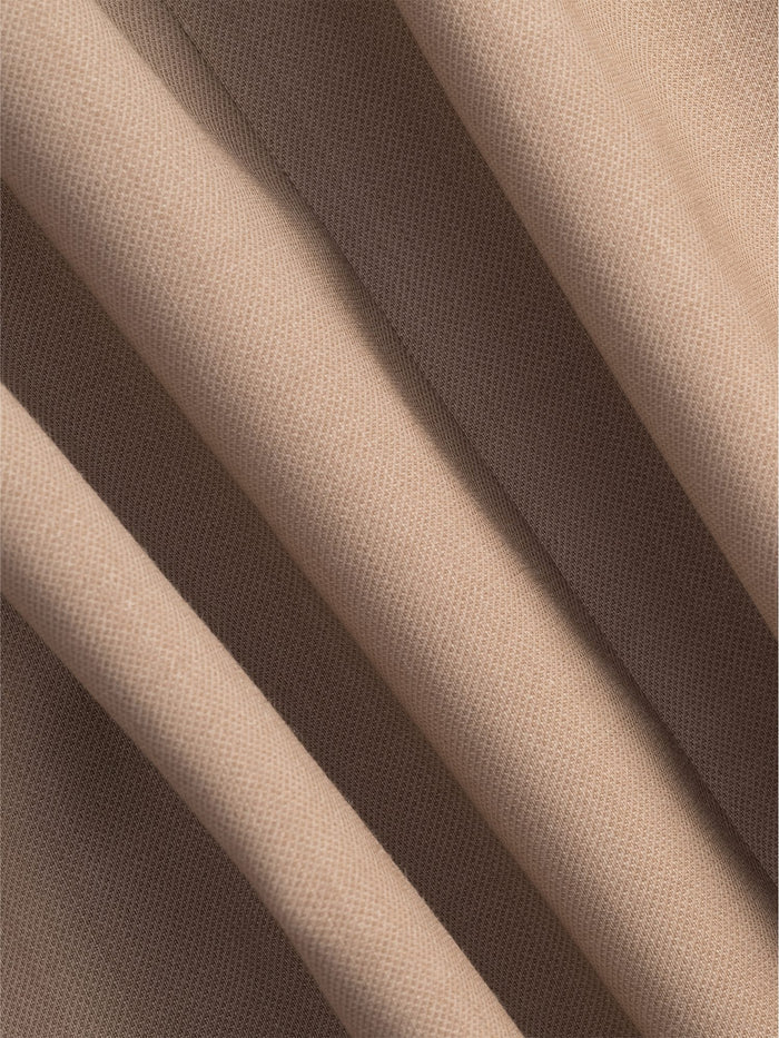 Close-up of camel suit fabric with soft folds and fine weave.