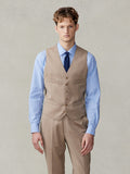 Man in a camel suit vest, light blue shirt, and navy tie, cropped front view.