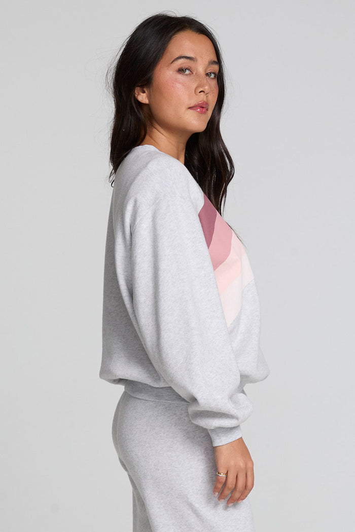 Side view of a woman wearing the Chaser  Cashbah Heather Grey Pullover and pants on a neutral background