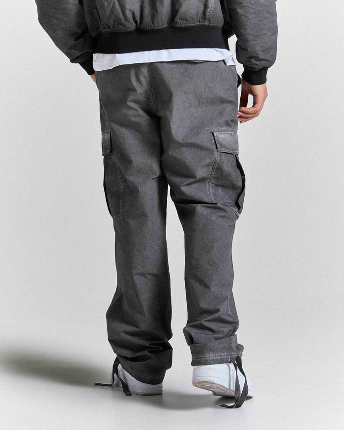 Person wearing gray cargo pants on a plain background