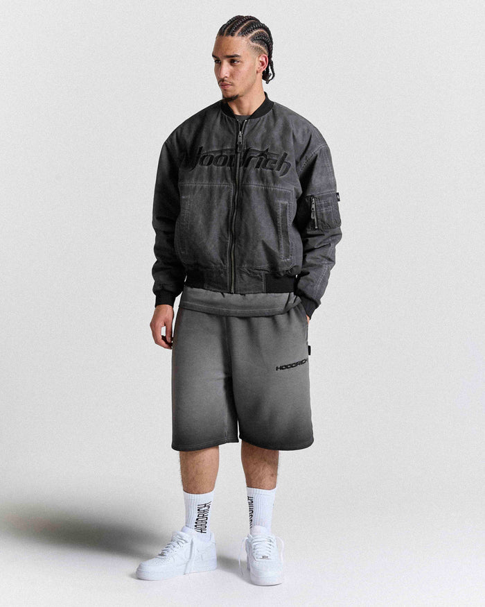 Male model wearing a gray jacket and shorts with 'Hoodrich' branding on a white background