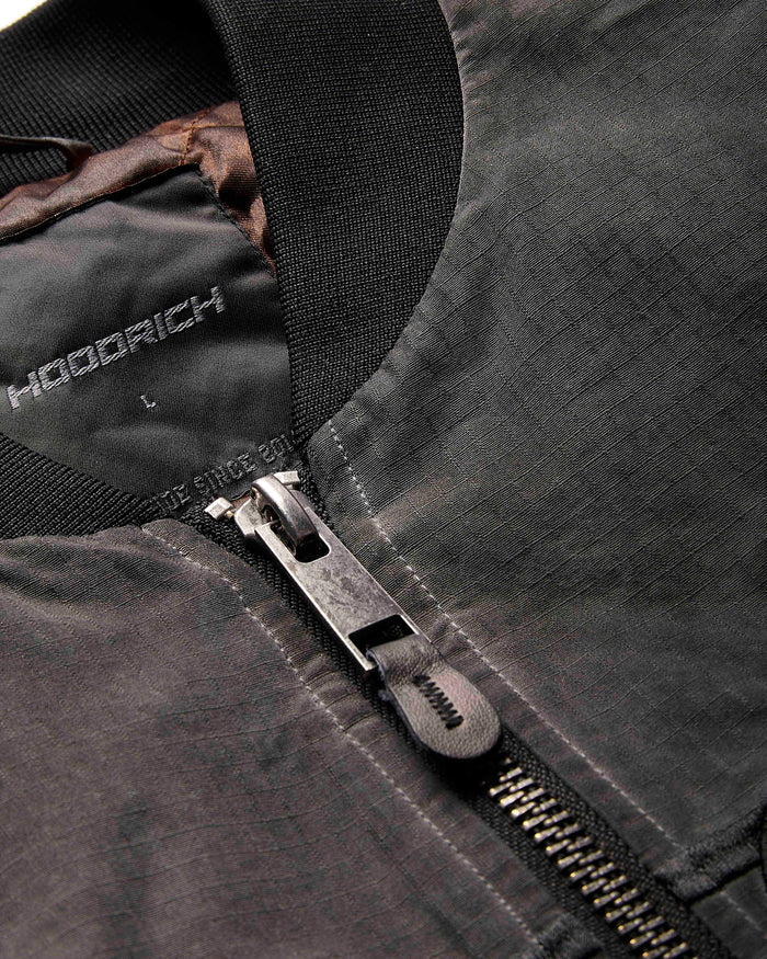 Close-up of a black jacket with a zipper, featuring the brand 'Hoodrich'.