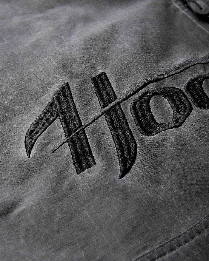 Close-up of a dark gray fabric surface with black embroidered Gothic-style lettering.