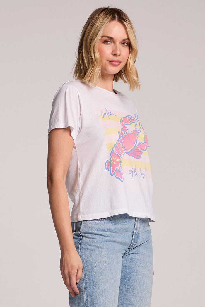 Side angle view of a woman wearing the Chaser  Catch Of The Day Tee on a neutral background with her hands down
