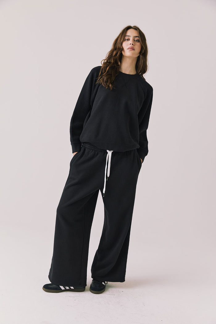 Full body view of woman wearing Chaser’s Cello True Black Pullover with matching Hazel Joggers on a white background
