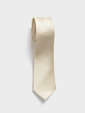 Champagne silk necktie rolled into a coil on a light background.
