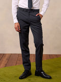 Cropped front view of a man in charcoal suit trousers, white shirt, and dotted tie, on a green turf platform.
