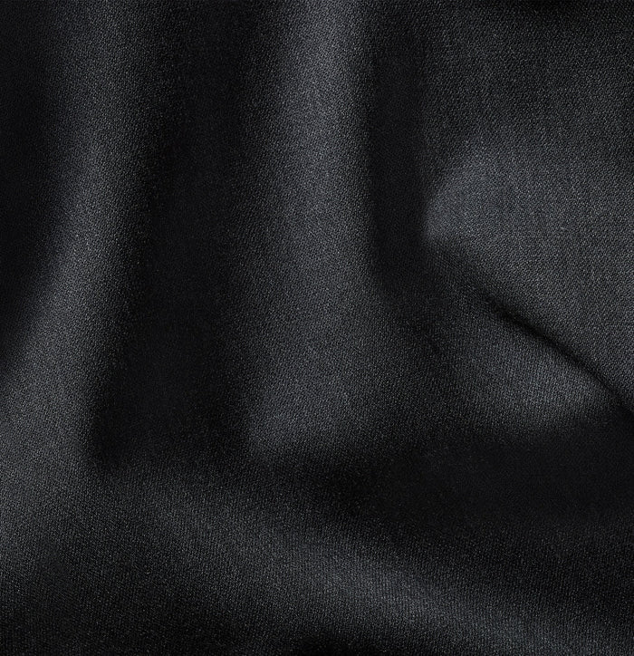 Close-up of charcoal suit fabric with folds and subtle sheen.