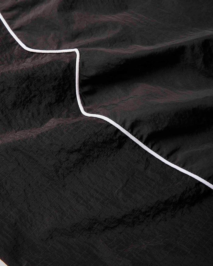 A close-up of a black crinkled fabric with a thin white stitched or printed line running diagonally across it.