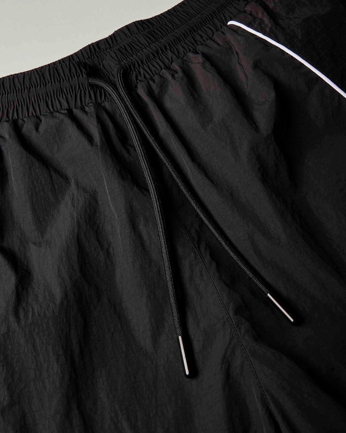 Close-up of black drawstring shorts with a white piping accent near the waistband.