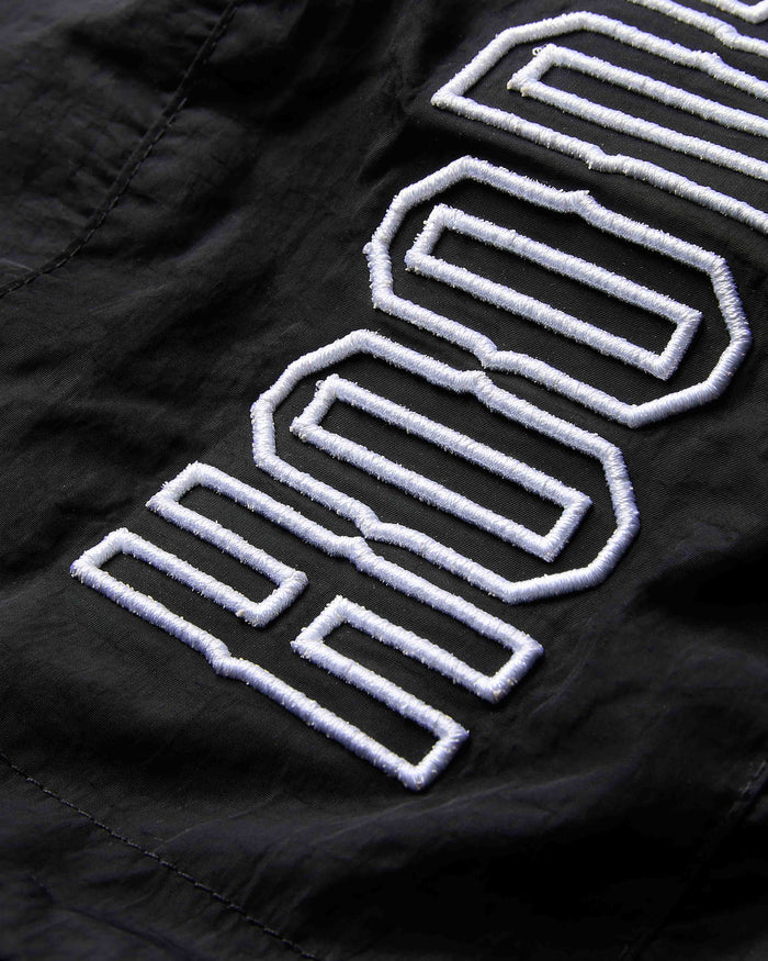Close-up of a black jacket with white embroidered logo on a dark background