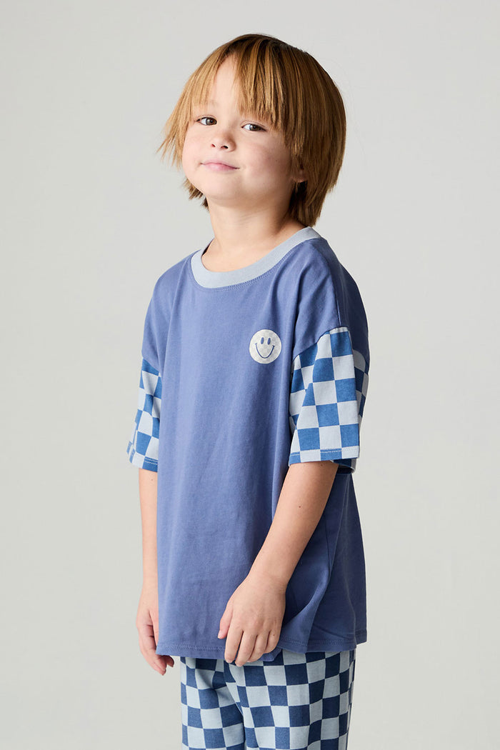 Side view of a boy wearing the Chaser Smileys Boys Tee on a neutral background with matching pants