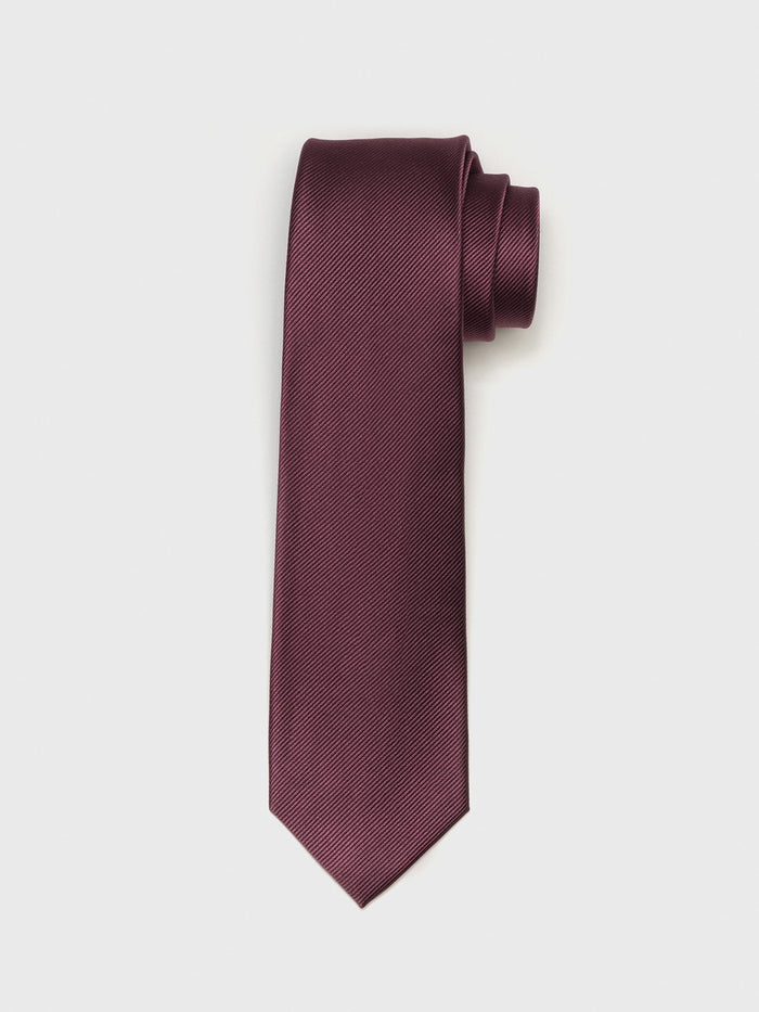 Chianti silk necktie with twill texture, rolled at the top, on a grey background.