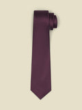 Chianti-red necktie with a fine dotted texture, rolled on a cream background.