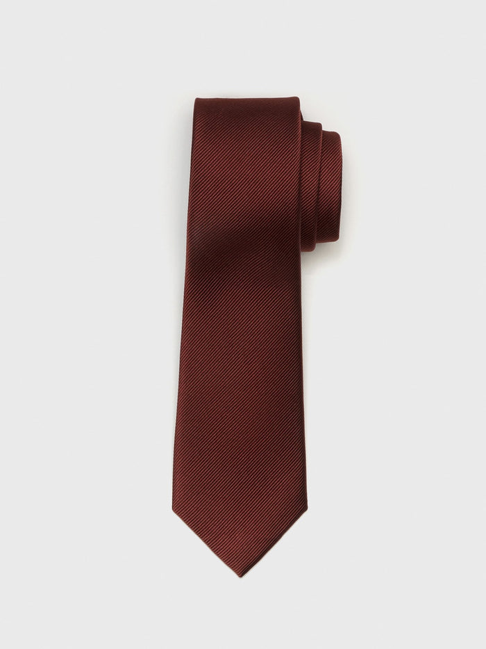 Cinnamon silk necktie with a textured weave, rolled up on a white background.